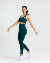 ترتدي المرأة سروال Smaragd Green Move بدون خياطة من WOMEN'S BEST وحمالة صدر رياضية.